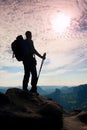 Silhouette of tourist with poles in hand. Hiker with big backpack stand on rocky view point above misty valley. Sunny daybreak Royalty Free Stock Photo