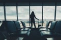 Silhouette tourist woman is talking on mobile phone while standing in passengers airport terminal Royalty Free Stock Photo