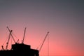 The silhouette of a tower crane perched on top of a building in the morning