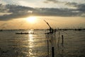 Silhouette of traditional fishing method using a bamboo square dip net with sunrise sky background