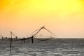 Silhouette of traditional fishing method using a bamboo square dip net with sunrise sky background