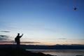 Silhouette of traveler controlling copter, drone makes aerial photo and video of sunset sky on beach.