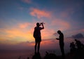 Silhouette of traveler controlling copter and photographing colorful sunrise. Man makes aerial photo and video of sunset sky on be