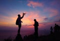 Silhouette of traveler controlling copter and photographing colorful sunrise. Man makes aerial photo and video of sunset sky on be