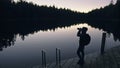 Silhouette traveler photographing scenic view in forest, river. Wood pier. One woman shooting nice dark magic night look