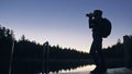 Silhouette traveler photographing scenic view in forest, river. Wood pier. One woman shooting nice dark magic night look Royalty Free Stock Photo