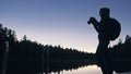 Silhouette traveler photographing scenic view in forest, river. Wood pier. One woman shooting nice dark magic night look Royalty Free Stock Photo