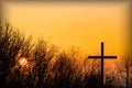 Religious cross and silhouette of tree branches on a sunset background. Royalty Free Stock Photo