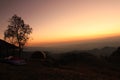 Silhouette of tree and mountain with orange sky and cloud background at sunset or sunrise time in Nan, Thailand. Royalty Free Stock Photo