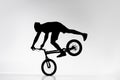 silhouette of trial biker performing front wheel balancing stunt on bicycle