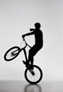 silhouette of trial biker standing on back wheel and pointing somewhere