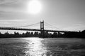 Silhouette of Triborough bridge over reflective river and buildings in black and white style