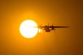 Silhouette of turboprop airplane taking off during sunset, flies wing through the disc of the sun. A trail of hot air from engines Royalty Free Stock Photo