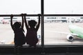 Silhouette of two asian child girls with backpack looking at plane and waiting for boarding in the airport Royalty Free Stock Photo