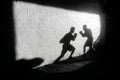 Silhouette of two boxers training on a brick wall in a dark urban setting Royalty Free Stock Photo