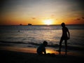 Silhouette of two unrecognizable boys playing in the beach at sunset Royalty Free Stock Photo
