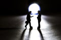 Silhouette of two business figurine walking towards each other in front of a small flashlight