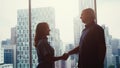 Silhouette of two businessmen talking and shaking hands standing by the window urban city view during beautiul sunset Royalty Free Stock Photo