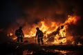 Silhouette of two firemen fighting a raging fire with huge flames of burning scrap