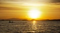 Silhouette of two fishermen on a small fishing boat with outboard motor on the ocean at nightfall with orange sunset. Royalty Free Stock Photo