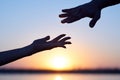 Silhouette Two hands, man and woman, reaching towards each other at sky sunset. Giving a helping hand. Royalty Free Stock Photo