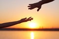 Silhouette Two hands, man and woman, reaching towards each other at sky sunset. Giving a helping hand. Royalty Free Stock Photo