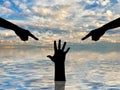 Silhouette of two hands showing a finger and condemning the hand of a sinking person asking for help