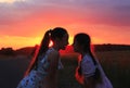 Silhouette of two little girls smiling on sunset. Sisters enjoyed a Holiday over blurred summer nature. Hhappy childhood concept Royalty Free Stock Photo