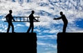 Silhouette two men carry a ladder to pave the way across the abyss for another man