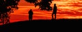 Silhouette of two men standing on the hill in sunset with vibrant orange sky Royalty Free Stock Photo