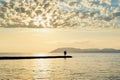 Silhouette of two people on the pier fishing in the sea at sunset against the mountains Royalty Free Stock Photo