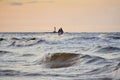 Silhouette of two unrecognizable persons standing on Mangalsala pier in wavy sea in sunset