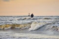 Silhouette of two unrecognizable persons standing on Mangalsala pier in wavy sea in sunset