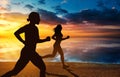 Silhouette of two women jogging on the beach at sunset