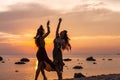 Silhouette of two young beautiful girls having fun on the beach at sunset Royalty Free Stock Photo