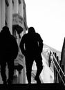 Silhouette of two young man with hands in pockets walking up the city subway stairs