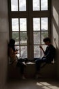 Silhouette of two young visitors on their telephone at Louvre Museum overlooking Pyramid, Paris France August 2015