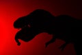 Silhouette of tyrannosaurus biting a human body on a red background