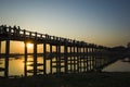 Silhouette of U Bein bridge with reflection in water at sunset with sunrays shining under bridge in Amarapura, Mandalay, Myanmar Royalty Free Stock Photo