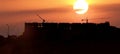 Silhouette of Under Construction Building with Two Cranes and Sunset in Background Royalty Free Stock Photo