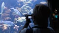 Silhouette of an unidentified man taking photograph of fish swimming in oceanarium