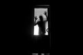 Silhouette of an unknown shadow figure on a door through a closed glass door. The silhouette of a human in front of a window at ni