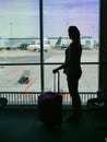 SILHOUETTE: Unrecognizable female tourist holding her bag and looking at runway. Royalty Free Stock Photo