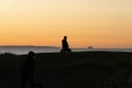 In silhouette unrecognizable person sitting on edge back-lit in golden hour