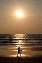 Silhouette of an unrecognizable small child holding a footaball on a golden sandy beach at sunset Royalty Free Stock Photo