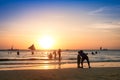 Silhouette of unrecognizable tourists and local people with father and son taking selfie at Boracay beach during sunset -