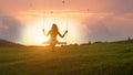 SILHOUETTE: Unrecognizable young woman swaying on swing at golden summer sunrise