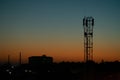 The silhouette of the urban buildings and a communications antenna tower of the mobile operator at sunset Royalty Free Stock Photo