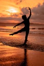 silhouette of a very slender ballerina doing ballet practice alone on the seashore with waves crashing at her Royalty Free Stock Photo