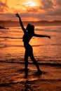 silhouette of a very slender ballerina doing ballet practice alone on the seashore with waves crashing at her